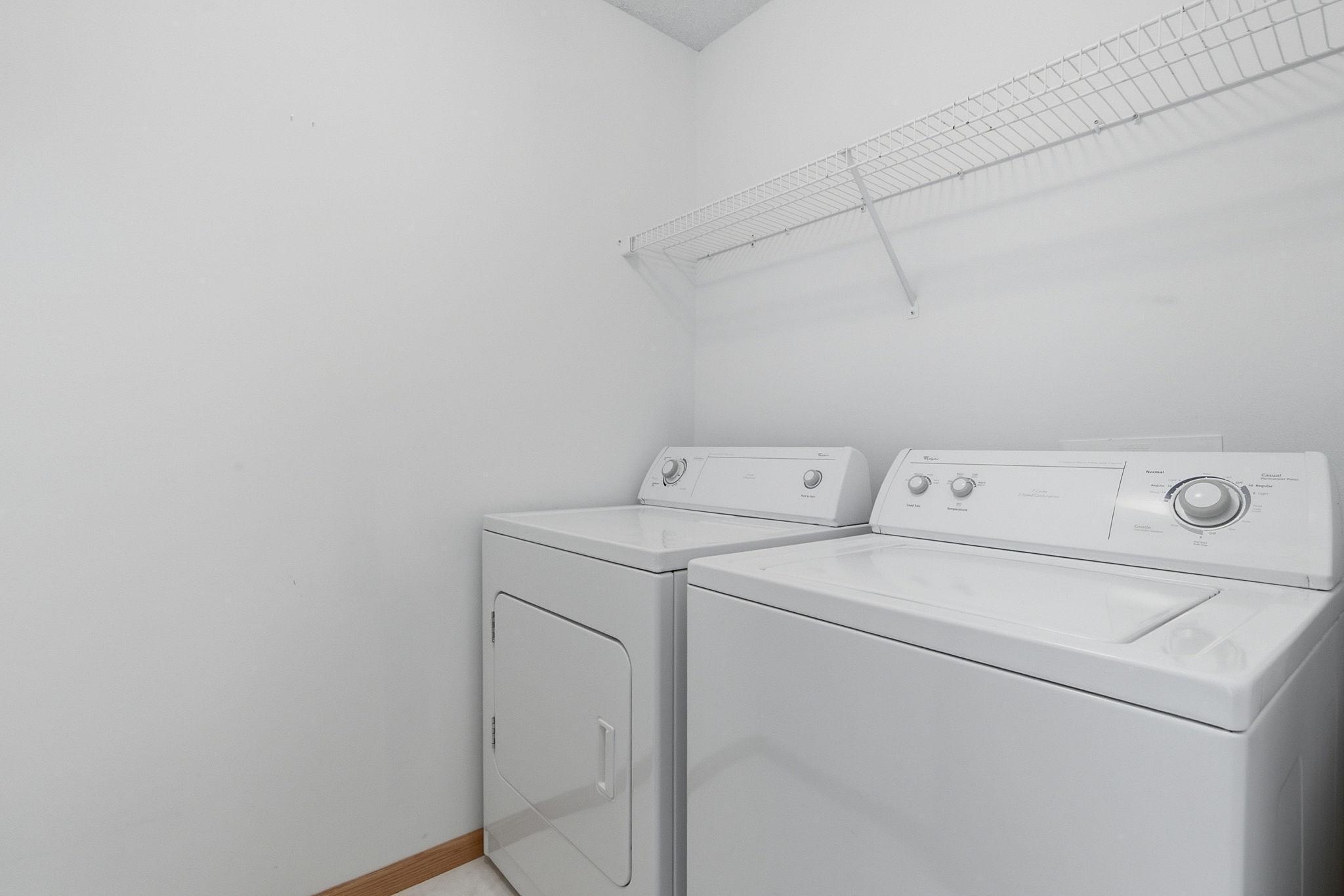 Upper level laundry room with washer, dryer, and shelving.
