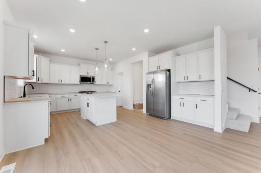 (Photo of an inventory home, actual homes finishes will vary) The stunning kitchen features a large center island, quartz countertops, LVP floors, stainless steel appliances, and more!