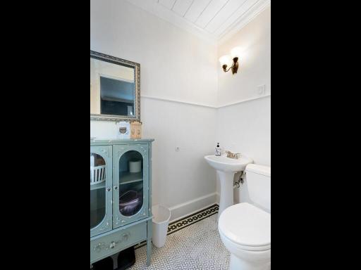 A charming updated attached half bath highlighted by original classic mosaic tile flooring.