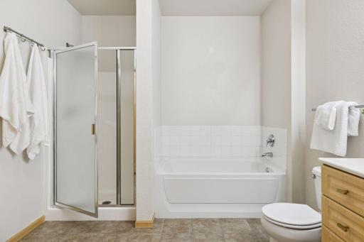 The bathroom is neutral white walls and tile floor. A separate tub and shower and a generous sized space.