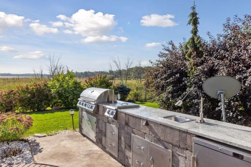 The outdoor kitchen is fully outfitted with grill stations, a sink, and cold storage, making it easy to host gatherings of any size.