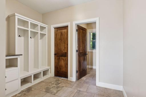 Off the kitchen, a spacious mudroom with coat storage and a half bath connects to the three-car garage, which is finished with a professional epoxy floor.