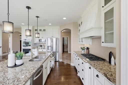 The kitchen delivers on both form and function with granite countertops, a large center island, stainless steel appliances, and a gas cooktop.