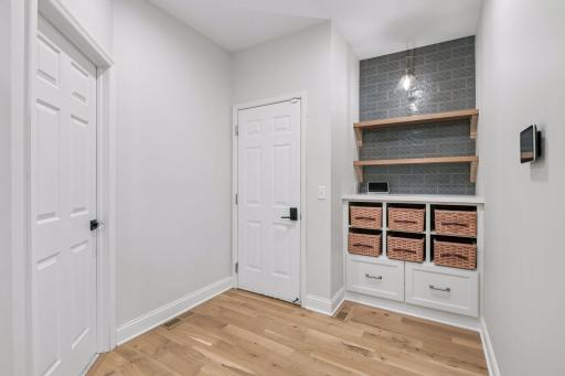Additional view of the mudroom with garage entry. Custom built-in cabinets, storage baskets (included), and open shelving.
