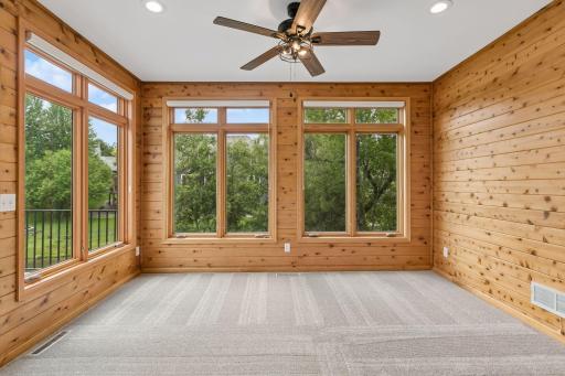 Wood paneled sunroom overlooking the secluded backyard pond.