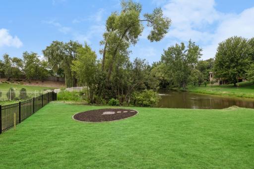 Backyard fire pit pad located next to the pond.