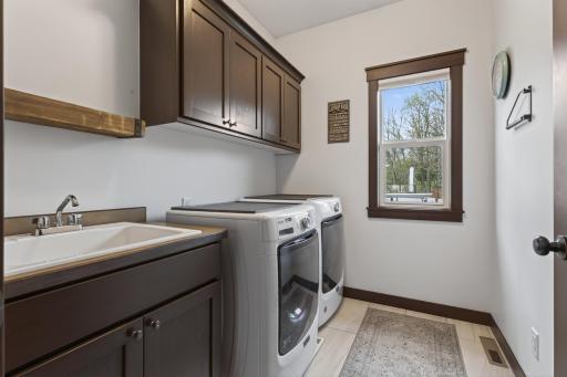 Main floor laundry room has a sink & cabinetry for storage.