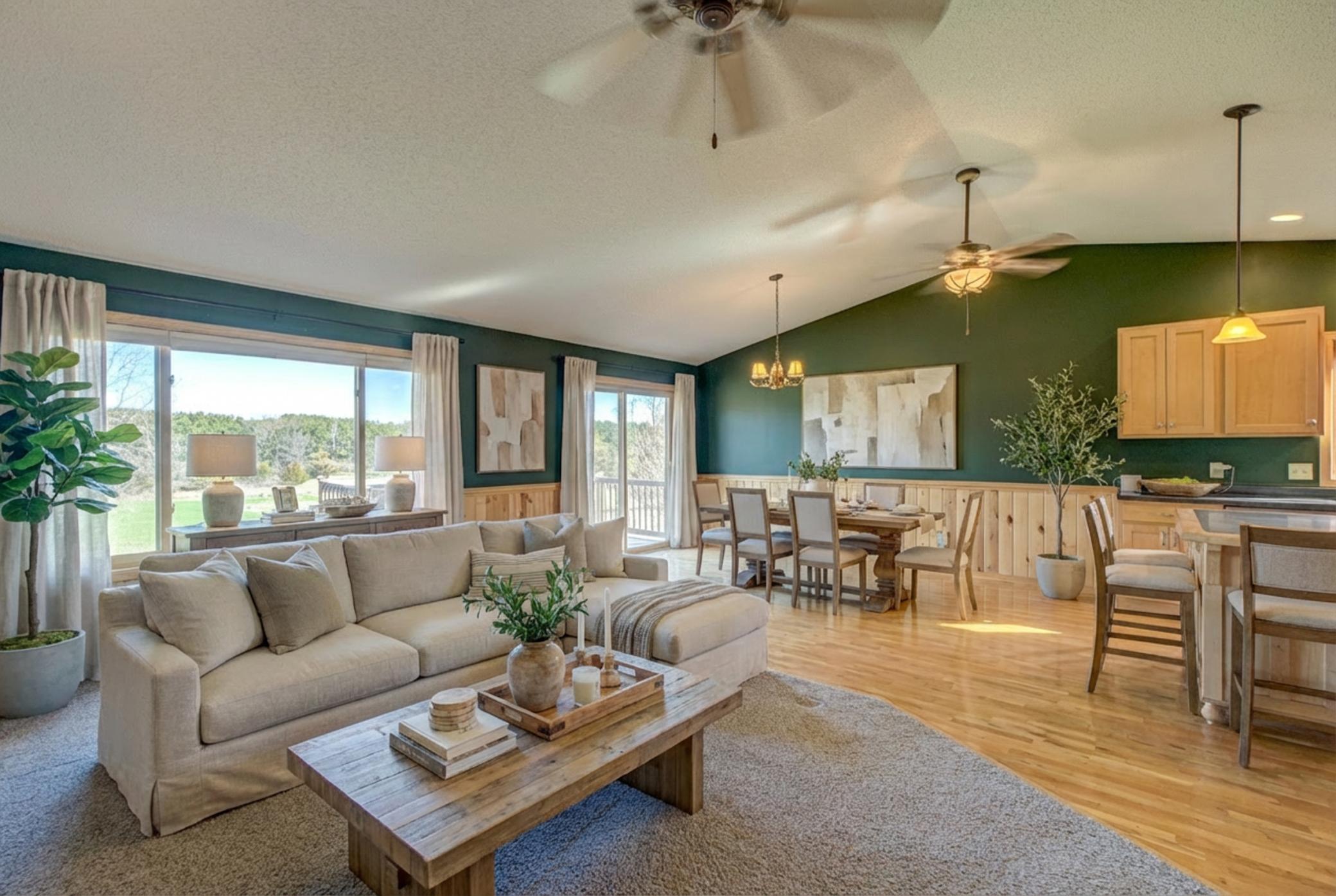 Wood floors carry through an open main level. The dining area opens to a walkout deck overlooking a spacious yard. (virtually staged)