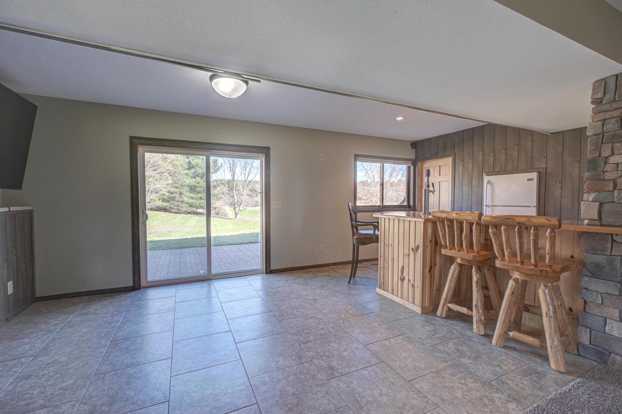 The finished lower level adds a second gathering space with a cozy fireplace, barnwood accents, and a custom bar with sink, fridge, and draft setup, along with direct access to the patio and backyard for easy indoor/outdoor living.