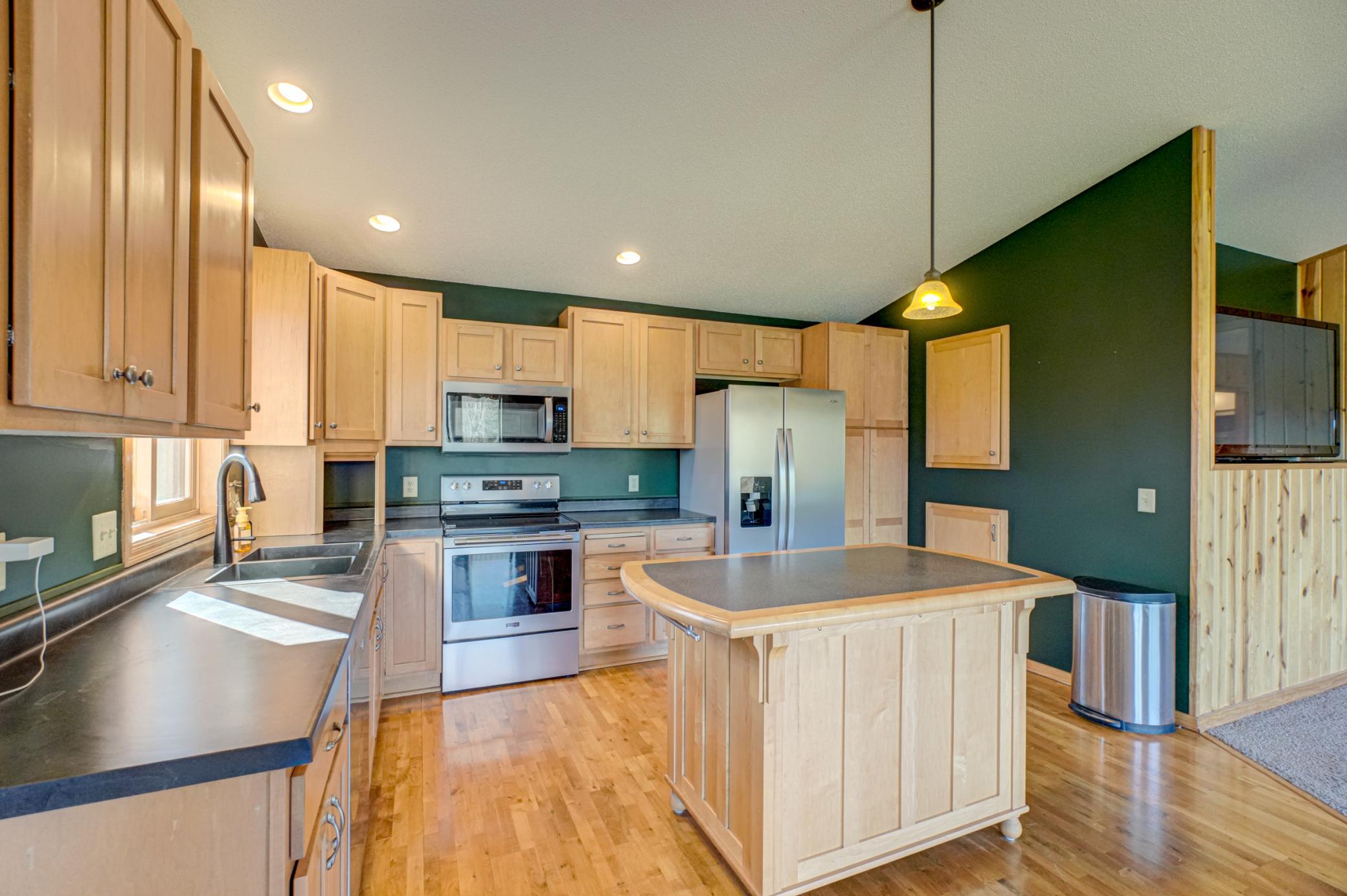Refreshed kitchen with new counters, sink, stainless steel appliances, a large center island, and ample counter and cabinet space.