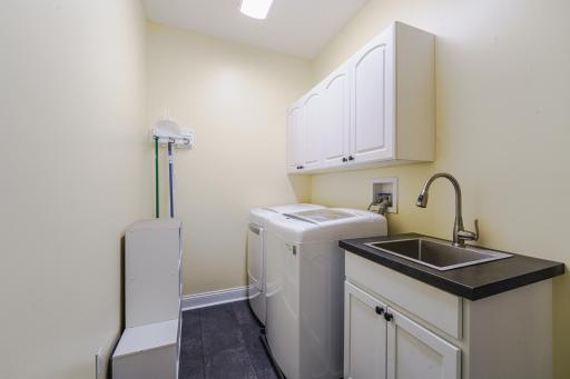 The main floor laundry space includes new LVT flooring and a new stainless steel utility sink and cabinet. The washer and dryer are included in the sale.