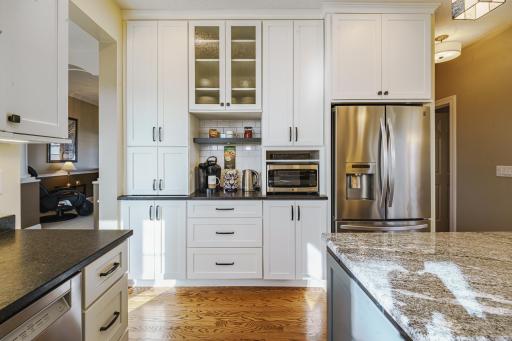 The remodel included stainless appliances including a vent hood, granite countertops, and a beverage station with a subway tile backsplash and floating shelves.