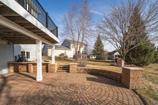 Circular paver patio with retaining wall and stairs. The yard has two apple trees - Honeycrisp and Cortland.