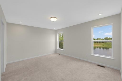 Spacious Owner's Suite featuring large windows overlooking the pond and surrounding green space.