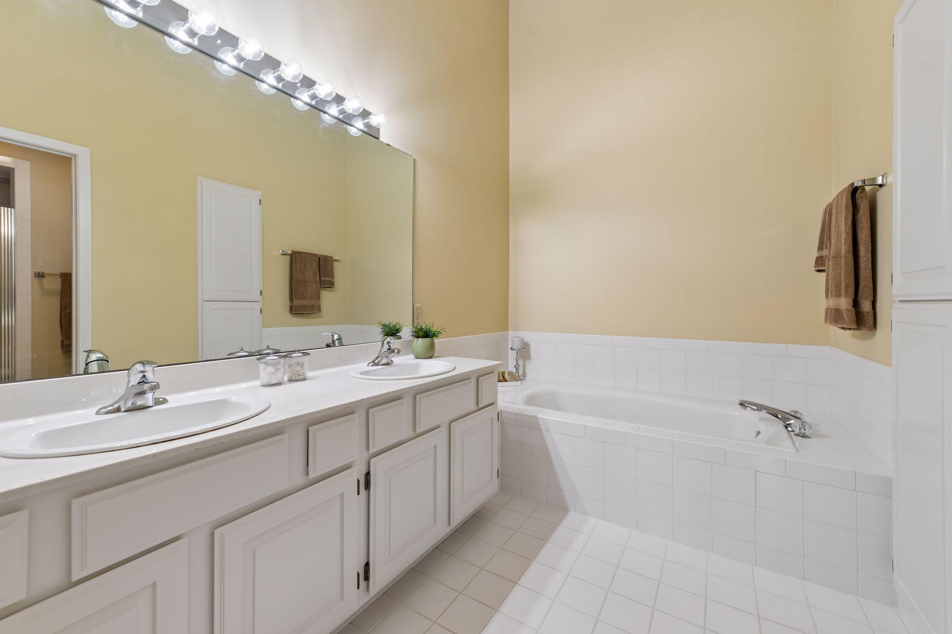 Private primary bathroom with dual vanity and separate jetted tub.