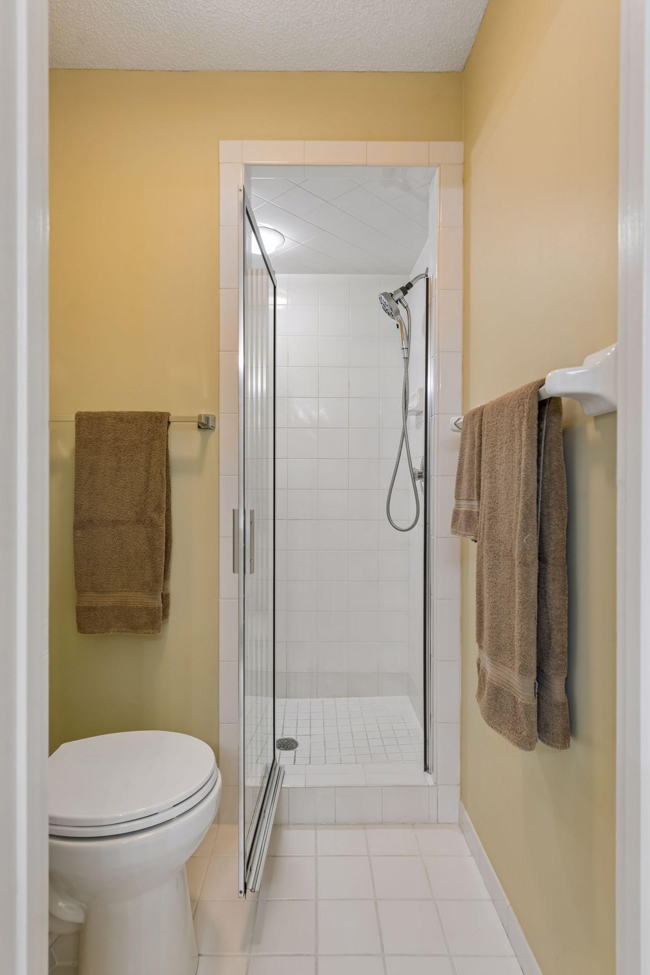 Dedicated area for toilet and walk-in shower in the primary bath. The floor and shower are in classic white tile for a neutral color palette.