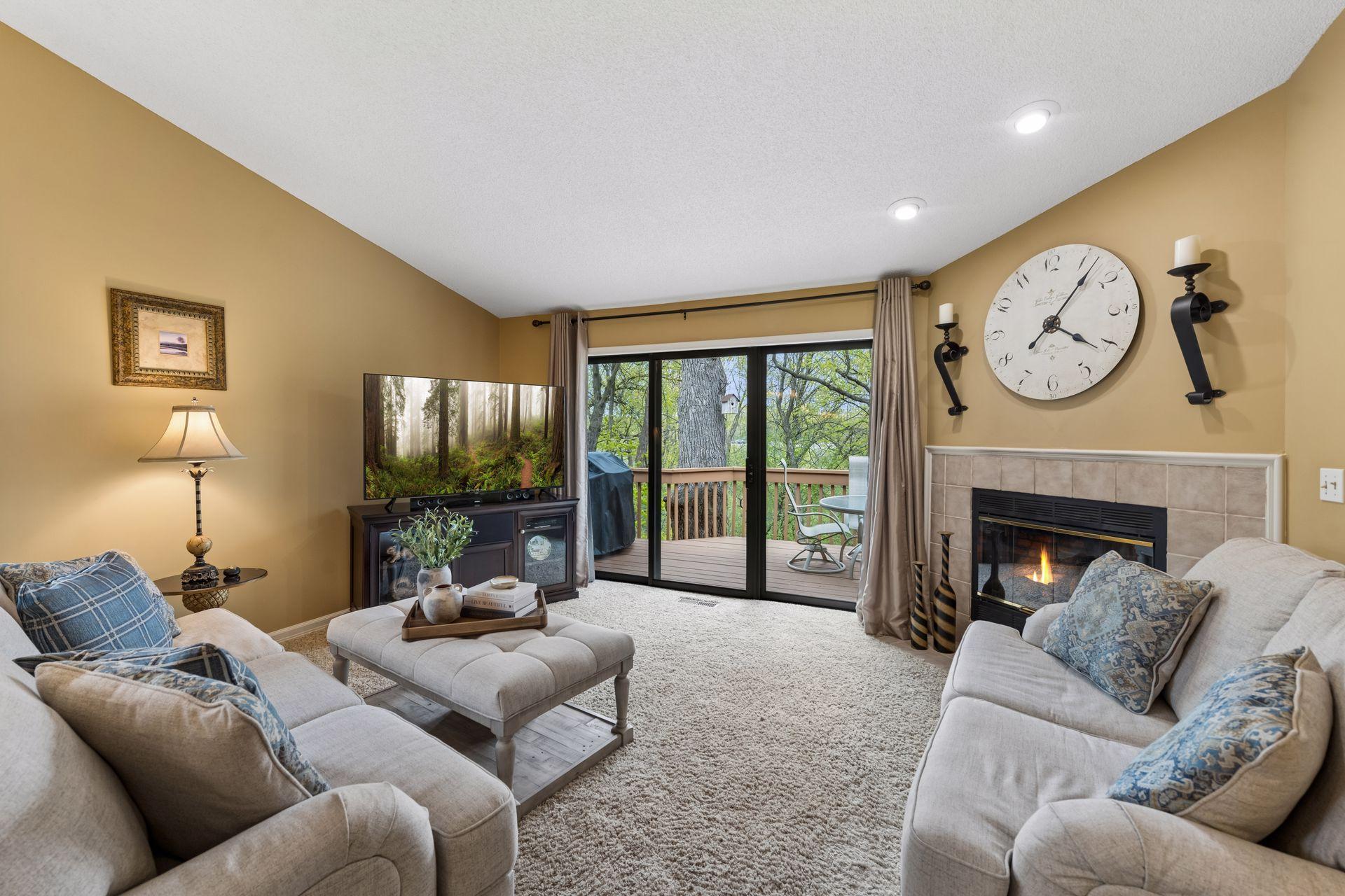 An inviting living room with vaulted ceilings, a cozy gas fireplace, and abundant natural light that fills the room from the oversized glass door that accesses the deck.