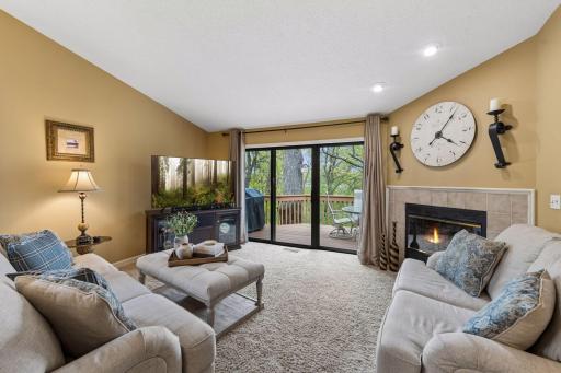 An inviting living room with vaulted ceilings, a cozy gas fireplace, and abundant natural light that fills the room from the oversized glass door that accesses the deck.