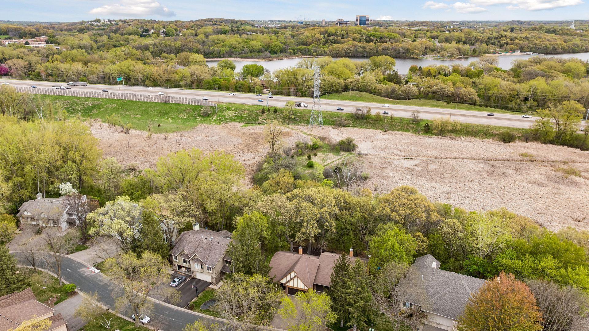 This aerial view shows that the dense tree line extends beyond the home. You can even see the walking trail in the wetlands.