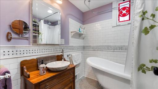 Upper-floor bath updated with white subway tile and marble vessel sink.