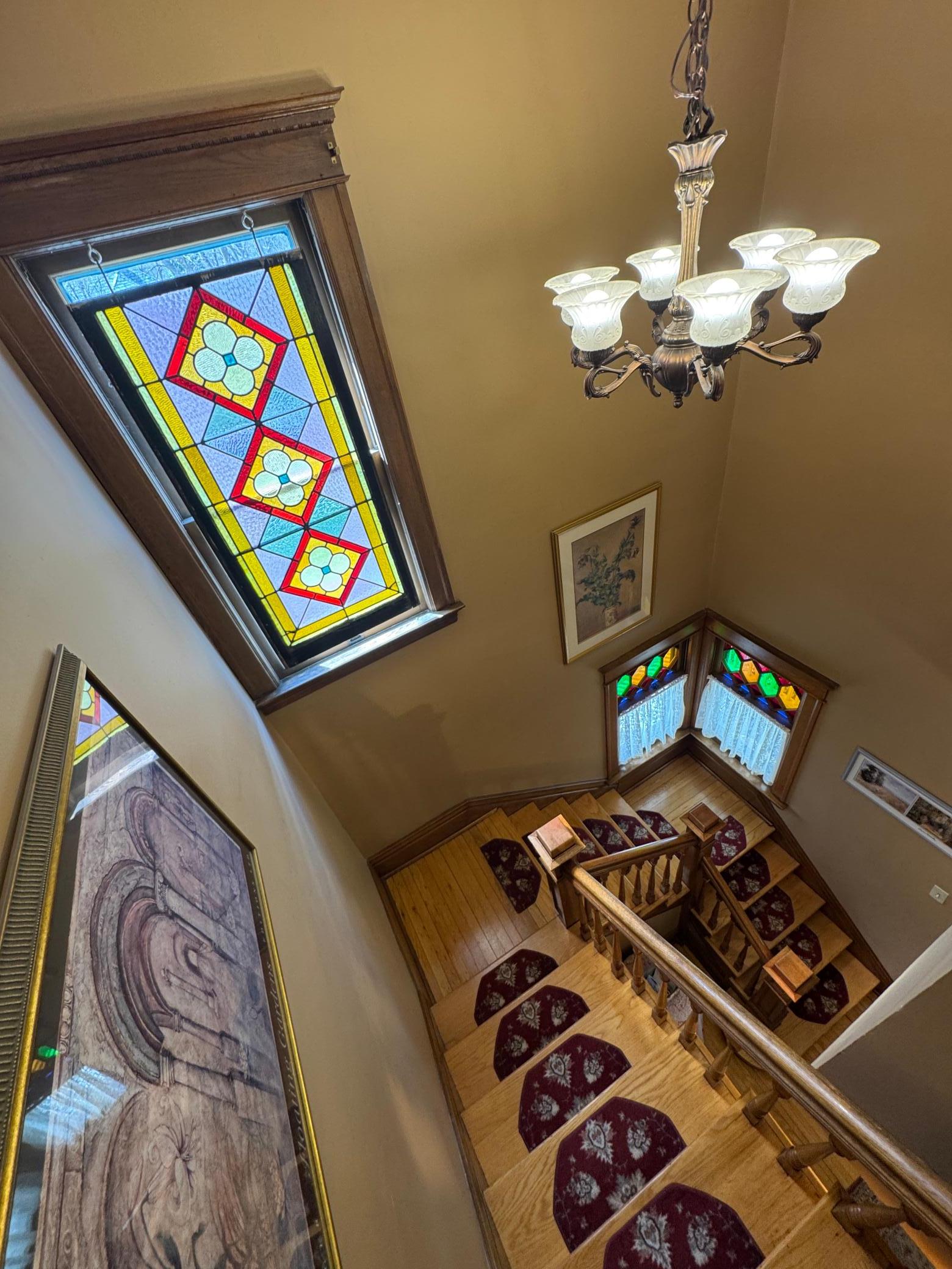 Stunning diamond-pattern quarry leaded glass windows with red and green cathedral accents, a defining characteristic of Queen Anne design