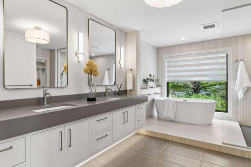 Master bath with heated floors, double vanity, custom built-ins & soaking tub with smart shade.