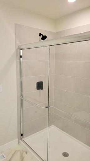 Spacious and bright, step-in tiled shower with beautiful glass door creates a fresh and relaxing feel.