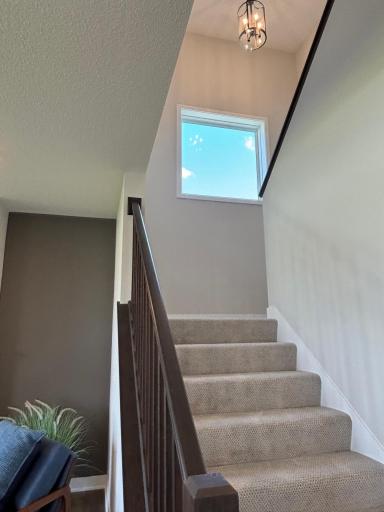 Gorgeous craftsman-styled open staircase with sophisticated wooden railing, stunning picture window and lovely accent lighting.