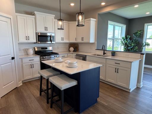 Designer kitchen with center quartz island, ceramic backsplash, elegant task lighting, separate pantry, and abundant natural lighting.