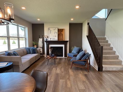 Warm and inviting great room centered around a modern fireplace with painted accent wall, and bright cheerful windows.