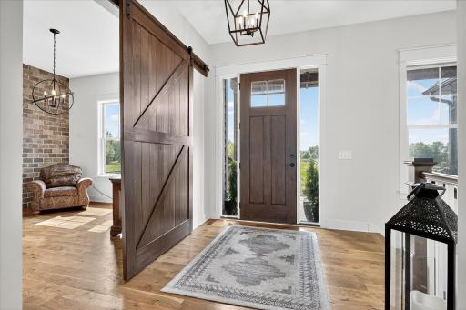 Inviting foyer with warm wood flooring, a sliding barn door, and abundant natural light.