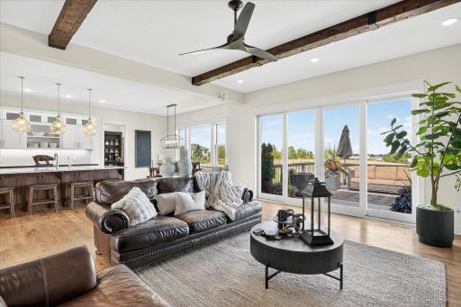 Bright and open living space featuring a stone fireplace, wood-beamed ceiling, and large windows with scenic views.