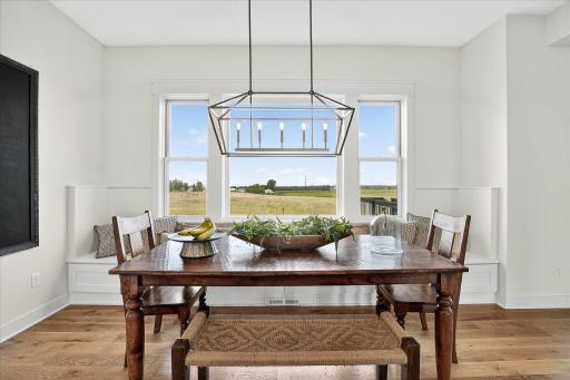 Bright dining space with built-in bench seating, large windows, and countryside views, highlighted by a modern chandelier.