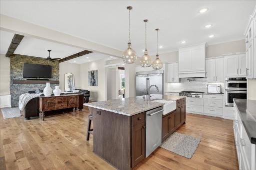 Bright and spacious design with a farmhouse sink, professional-grade appliances, and seamless flow into the living area with stone fireplace.