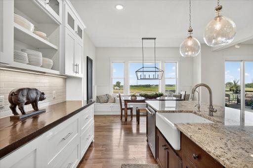 Stylish kitchen with granite countertops, pendant lighting, and a large island with seating, flowing into the dining area with built-in bench seating and picture windows.