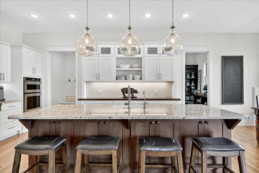 White cabinetry with glass accents, high-end appliances, and ample storage make this kitchen a true centerpiece.