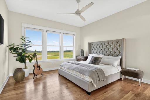 Sunlit primary bedroom retreat with wide windows overlooking the property, hardwood flooring, and a clean, modern design.