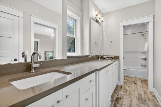 Jack - and -Jill full bathroom with double vanity with quartz counters and ample storage, paired with a large mirror and stylish lighting.