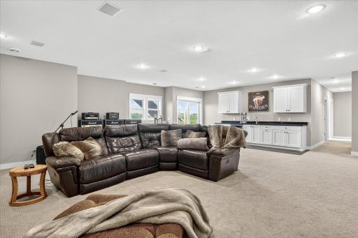 Spacious layout with plush carpeting, wet bar, and multiple seating areas, ideal for entertaining or relaxing.