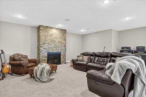 Features a stone fireplace, large windows, and sliding glass doors that walk out to the backyard.