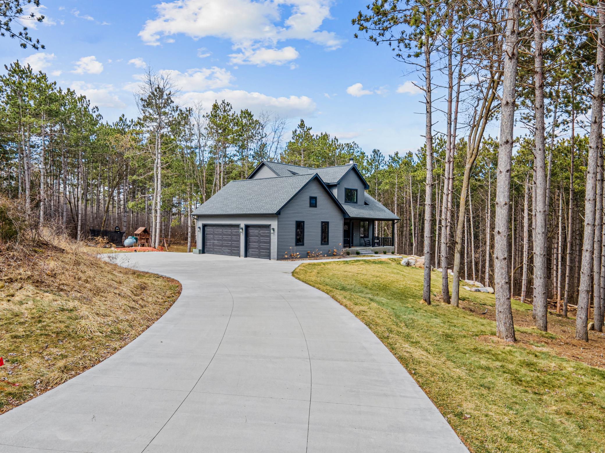 Long, curved driveway approaching the home through mature trees, creating a private setting