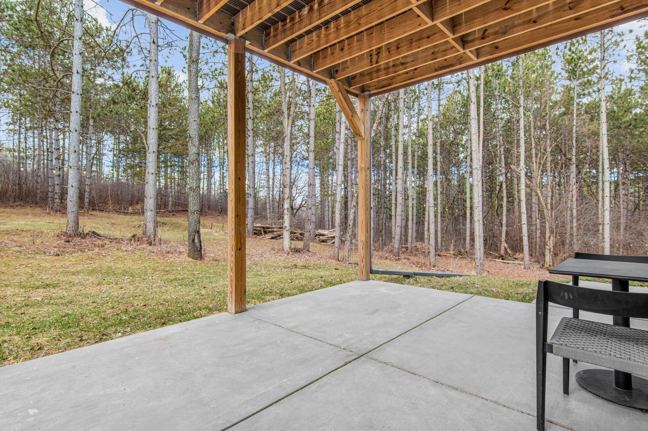 Covered patio offering shaded outdoor space with peaceful wooded views