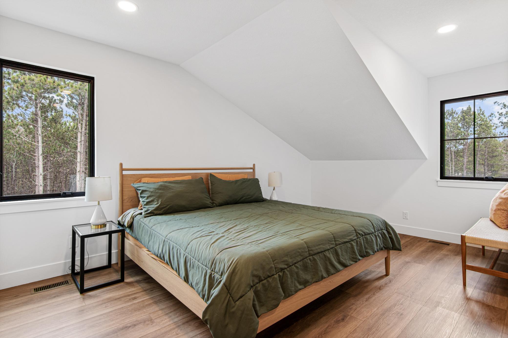 Spacious primary bedroom with vaulted ceilings, abundant natural light, and a peaceful setting