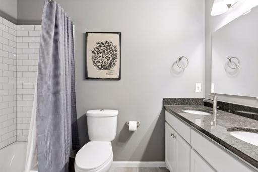 Full primary bath with granite dual vanity, tile surround and flooring.