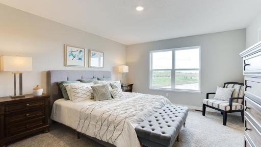 This primary ensuite boasts an enormous walk-in closet and double sinks in the bath! The primary in this home will have fantastic pond views! *Photo is of a model home, colors may vary in actual home.