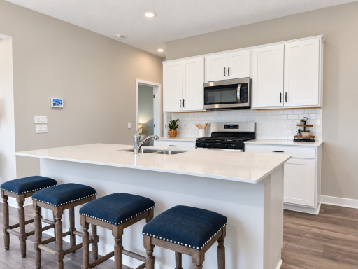 Quartz countertops, stainless steel appliances, and a gas range add the perfect finishing touch to this spacious kitchen.