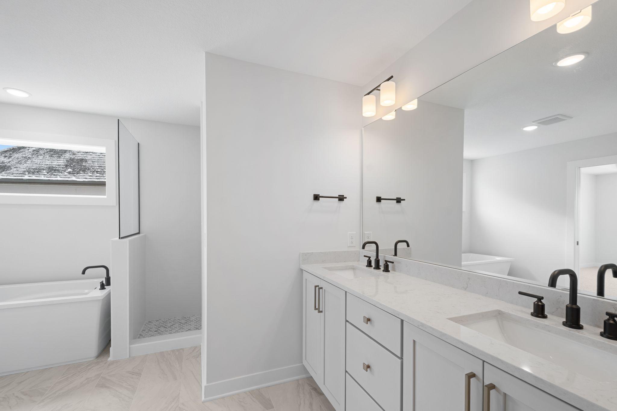 Primary bathroom with walk-in tile shower, freestanding soaker tub, dual vanities and walk-in closet