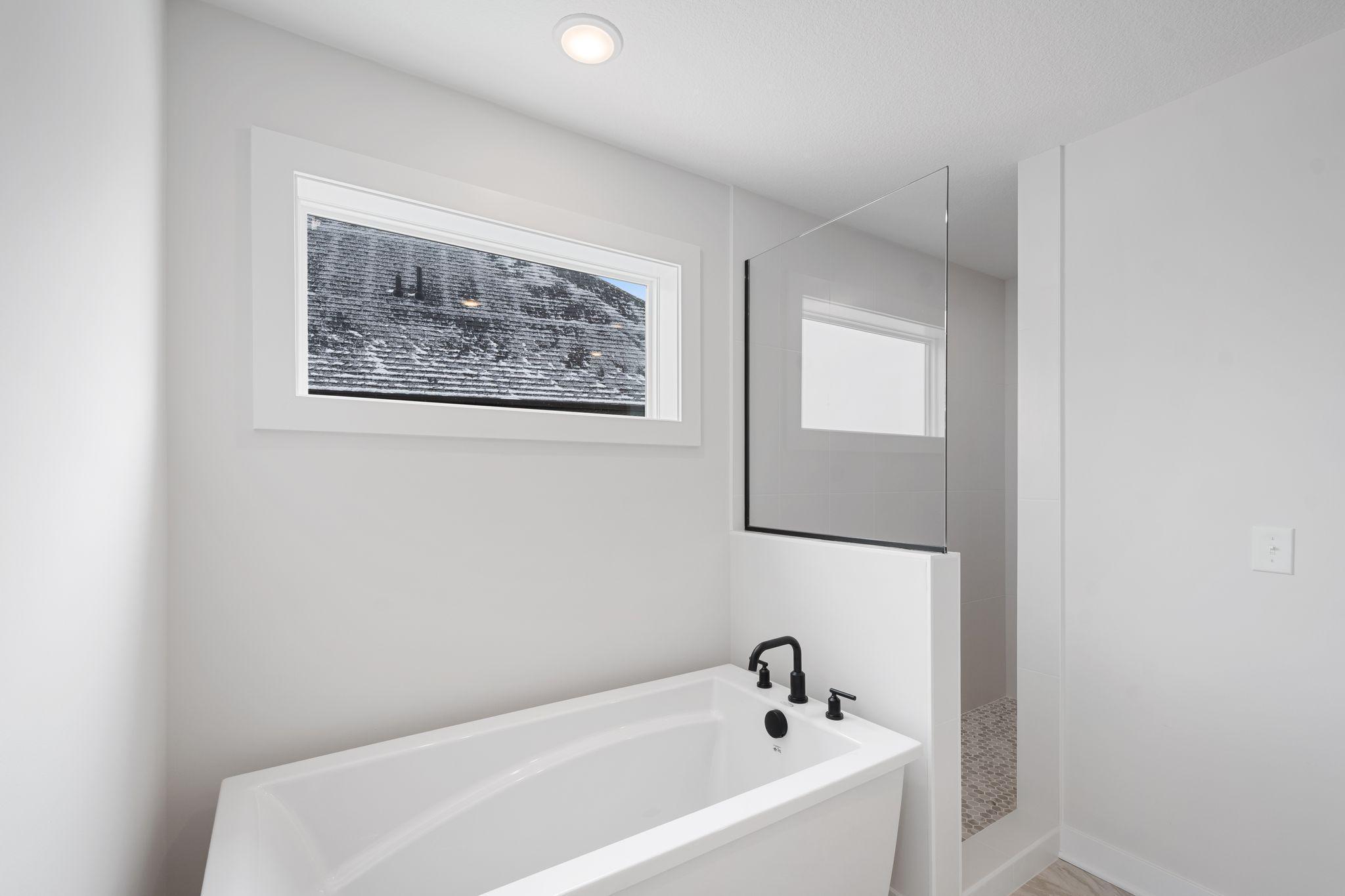 Primary bathroom with walk-in tile shower, freestanding soaker tub, dual vanities and walk-in closet