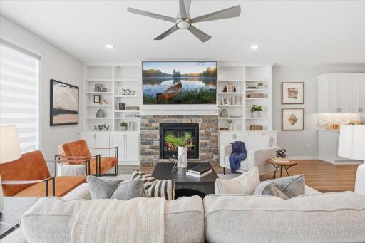 A stone surround gas fireplace flanked by custom built-ins is the focal point of the living room.