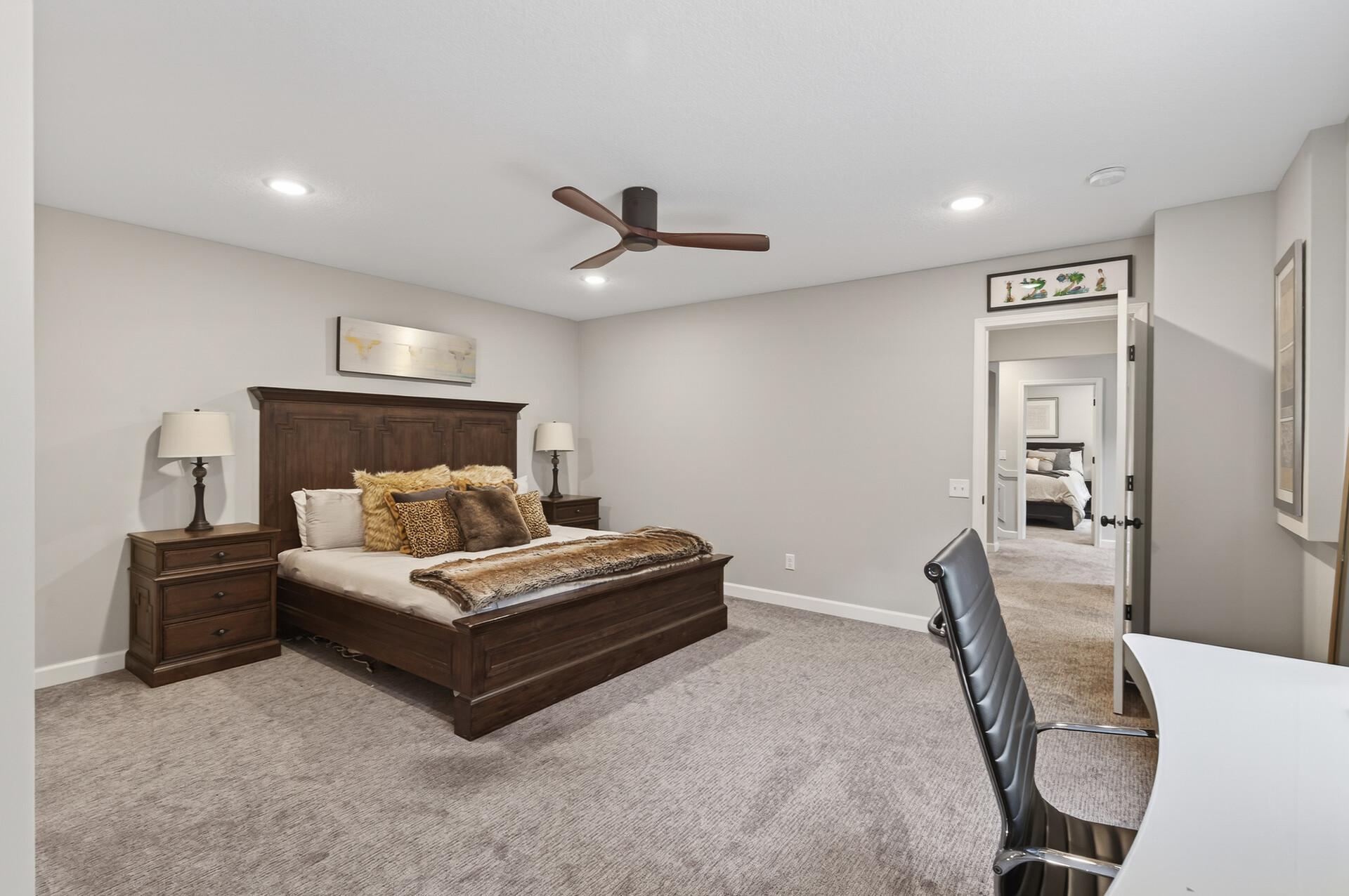 Recessed lighting and a sleek ceiling fan elevate this generously sized bedroom.